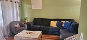 Ein Wohnzimmer mit einem dunkelgrauen Sofa, einem Holztisch und einem grauen Sessel.