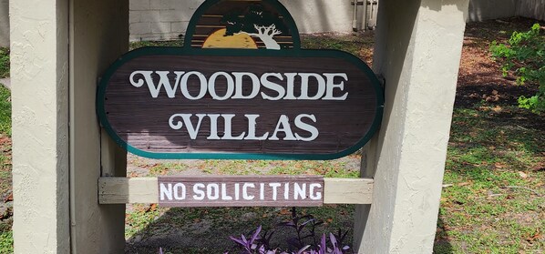 A wooden sign with 'WOODSIDE VILLAS' and 'NO SOLICITING' written on it.