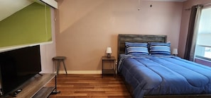 Une chambre à coucher avec un lit, des tables de chevet, une lampe et un téléviseur.