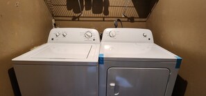 Two front-loading washing machines in a laundry room with a tiled ceiling. - Cozy 2BR/2BA Gainesville Retreat Near UF & Shands (Gainesville)