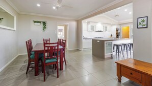 A spacious dining area with a wooden table and chairs, a kitchen with white cabinets, and a ceiling fan. - The Ritz, Family Pool Home, Dubbo (Dubbo)