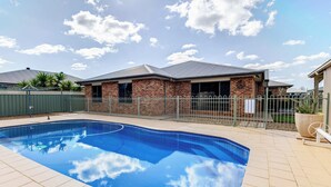 A swimming pool with a curved edge, surrounded by a paved deck. - The Ritz, Family Pool Home, Dubbo (Dubbo)