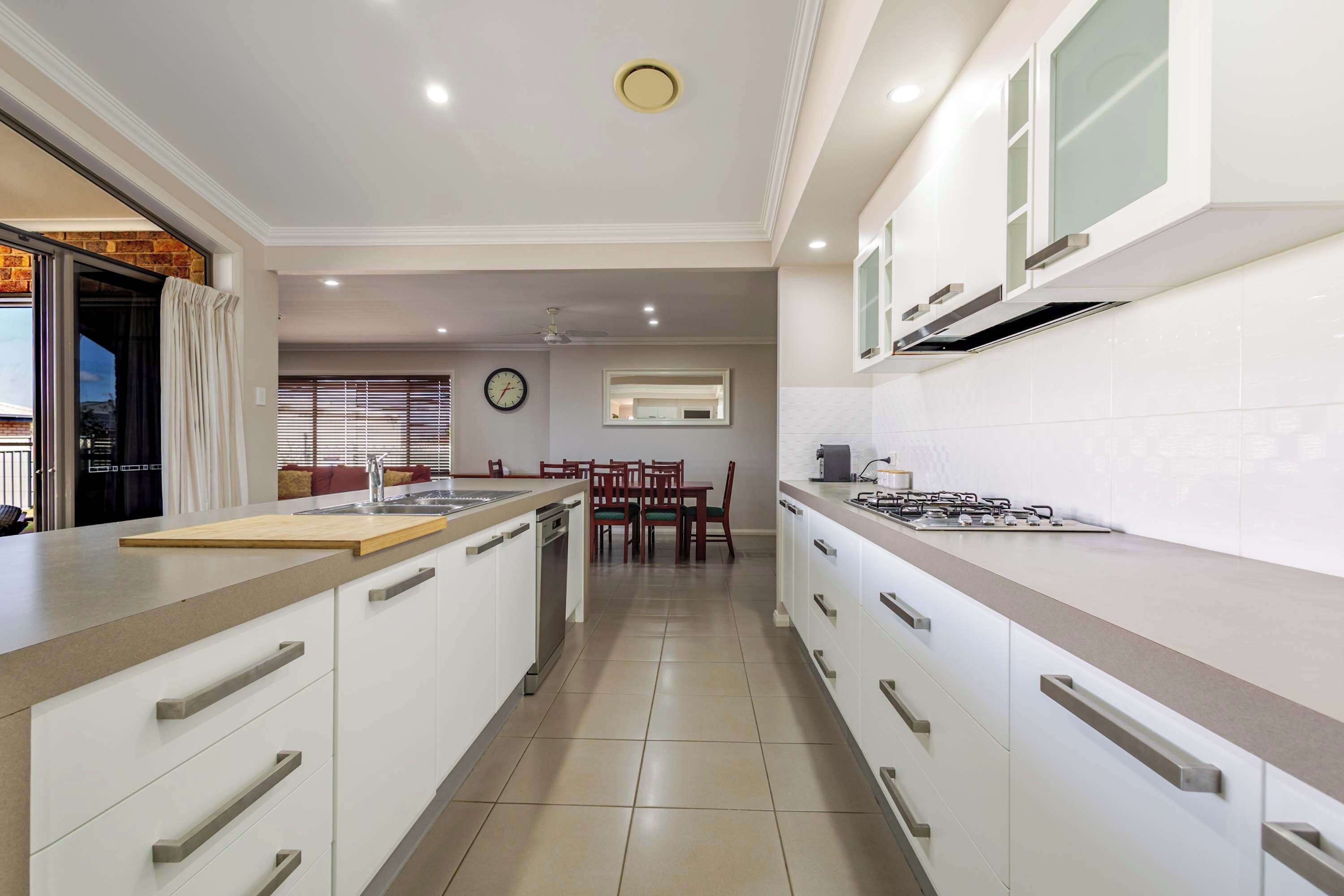 Una cocina moderna con armarios blancos, una isla central y un comedor con mesa y sillas.