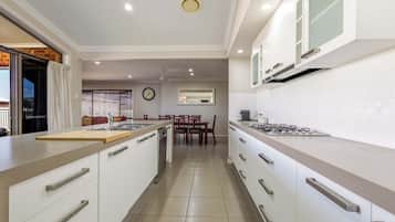Una cocina moderna con armarios blancos, una isla central y un comedor con mesa y sillas.