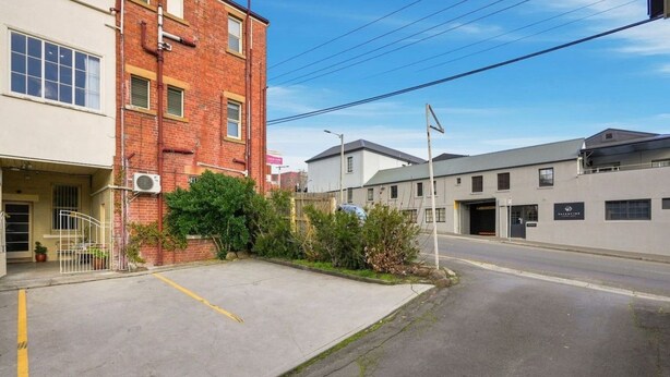 A parking lot with a building on the left and a street on the right. - Edinburgh - Queen Room + Free Parking (Hobart)