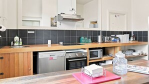 A modern kitchen with a wooden countertop, stainless steel appliances, and a large mirror above the sink. - Edinburgh - Queen Room + Free Parking (Hobart)