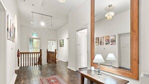 A spacious hallway with a wooden staircase, a large mirror, and a patterned rug. - Edinburgh - Queen Room + Free Parking (Hobart)