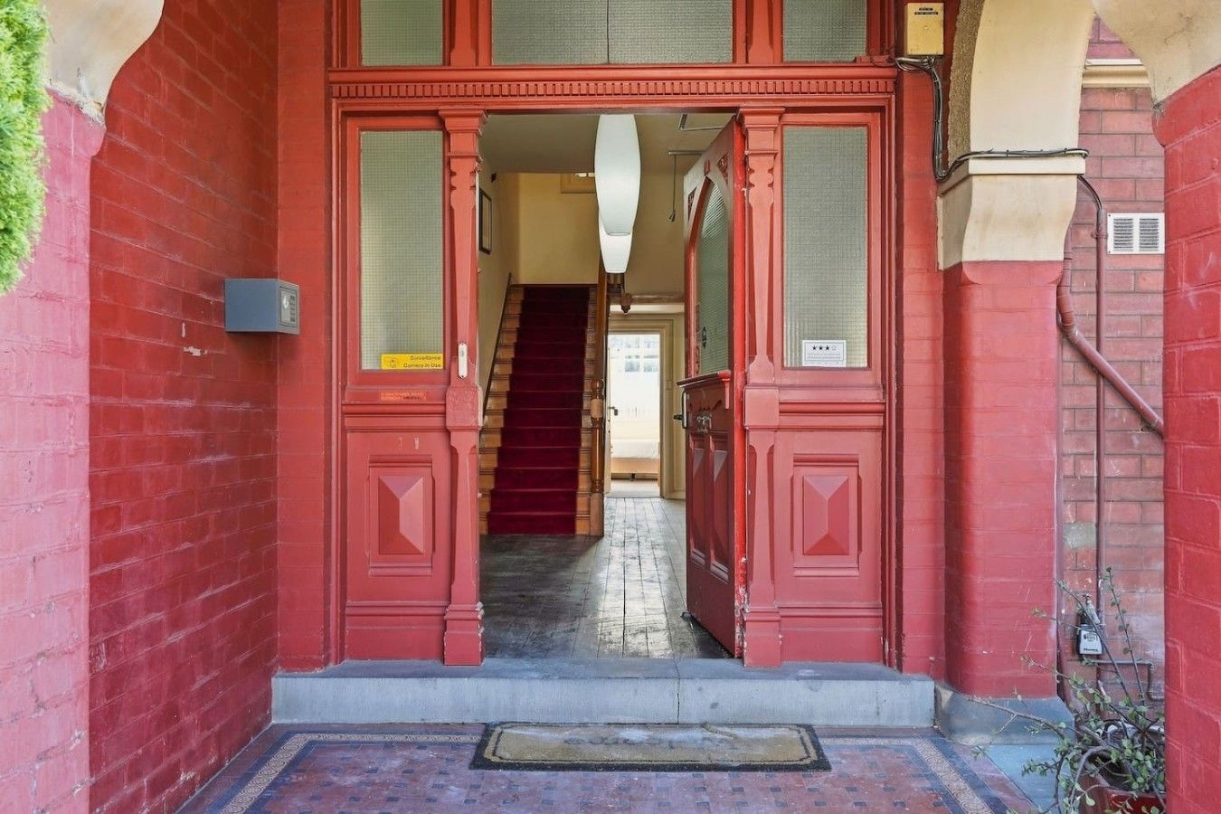 A red double door entrance with a staircase leading to an upper floor.
