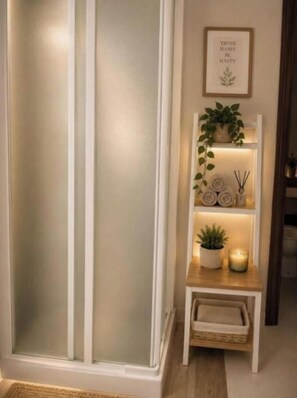 A room with a frosted glass door, a shelf with decorative items, and a framed inspirational quote on the wall.