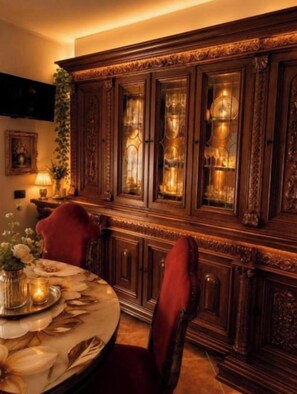 A dining area with a round table, red upholstered chairs, and a dark wooden cabinet with glass doors.