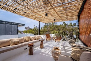 An outdoor seating area with a wooden pergola, cushioned seating, and decorative vases. - Villa Scorpia 4 Bingin (Pecatu)