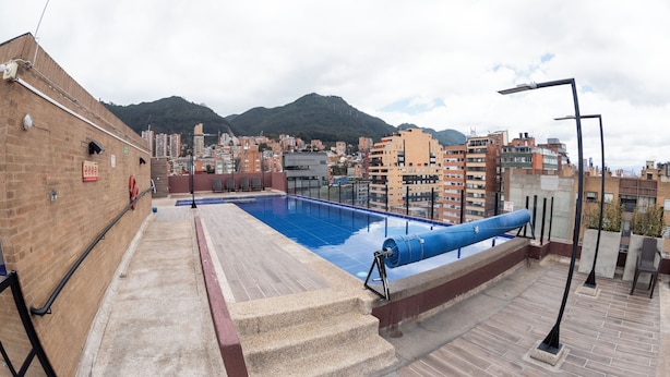 A rooftop swimming pool with a view of a cityscape and mountains in the background. - Punto Chapinero - Zona Gourmet (Bogotá)