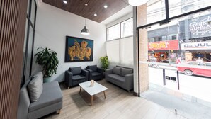 A modern interior with a seating area, a painting, and a view of the street outside. - Punto Chapinero - Zona Gourmet (Bogotá)