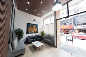 A modern interior with a seating area, a painting, and a view of the street outside. - Punto Chapinero - Zona Gourmet (Bogotá)