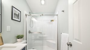 A modern bathroom with a glass-enclosed shower, a white toilet, a sink with a white countertop, and a potted plant. - Secluded Luxury Escape, Hot Tub, Fire Pit, Game Room & Yoga, Walk to Town (Woodstock)