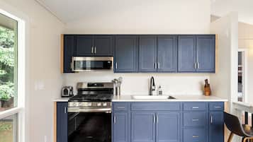 Une cuisine moderne avec des meubles bleu foncé, des appareils en acier inoxydable et un plancher en bois.