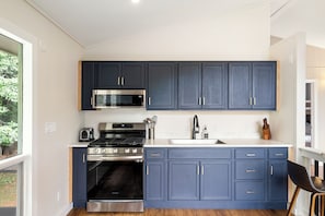 Une cuisine moderne avec des meubles bleu foncé, des appareils en acier inoxydable et un plancher en bois.