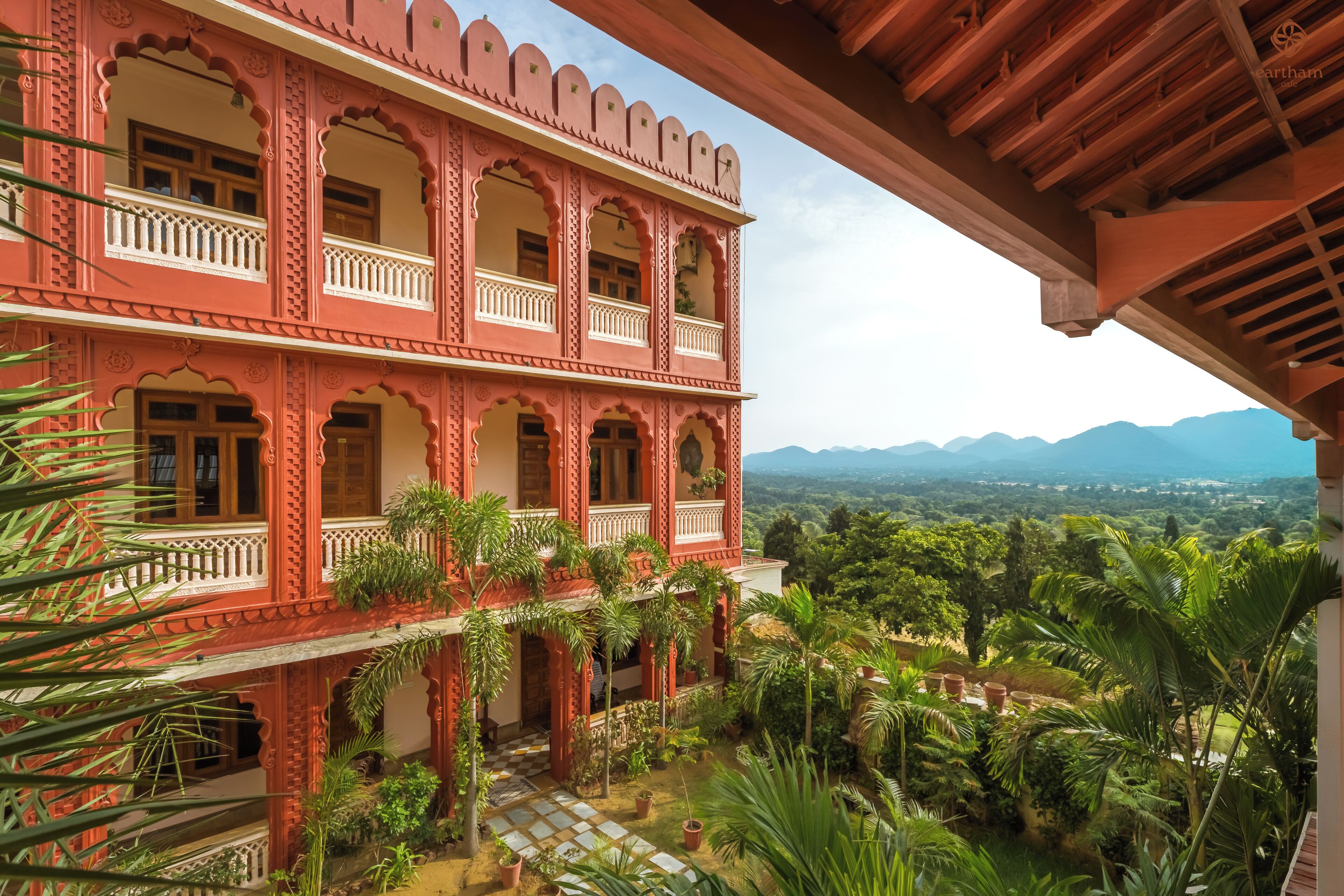 A multi-story building with balconies and a view of a mountainous landscape.