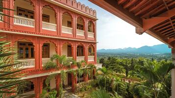A multi-story building with balconies and a view of a mountainous landscape.