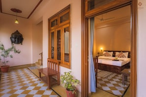 Habitación de hotel con piso a cuadros, cama de madera, mesita de noche, planta en maceta y una escultura de cabeza de Buda.