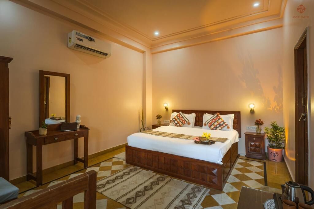 Une chambre d’hôtel équipée d’un lit, d’une table de chevet, d  ’un miroir, d’un climatiseur et d’une petite plante en pot.