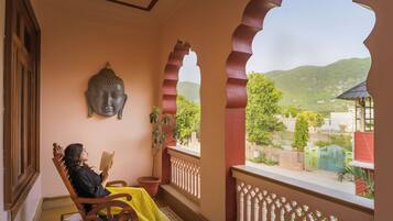 Una habitación con una estatua de Buda, una persona leyendo y vistas a zonas verdes y colinas.