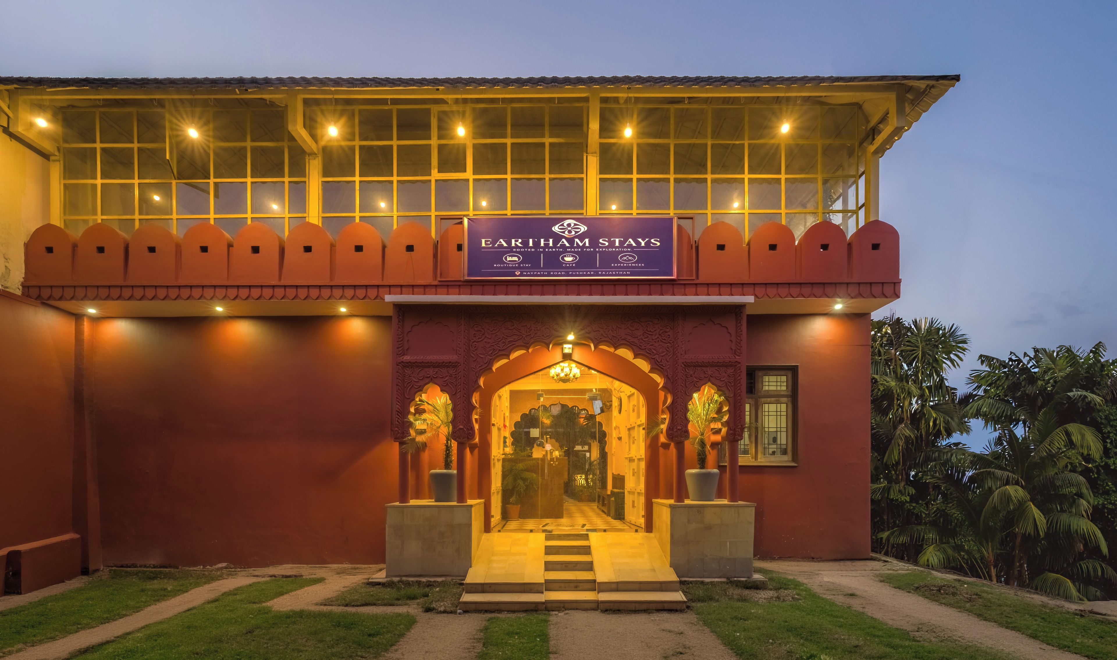 A hotel entrance with a signboard, a covered walkway, and a pathway leading to the entrance.