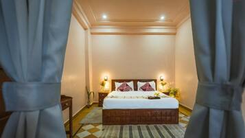 Habitación de hotel con cama, lámparas de noche, mesita de noche y alfombra estampada.