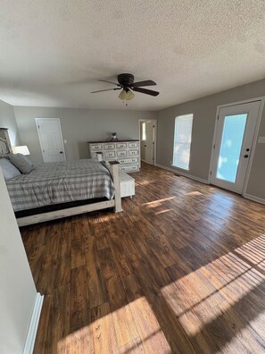 A bedroom with a bed, dresser, ceiling fan, and a view of the outside through a door. -  Can hunt on TVA land  Hunters and Fishermans Guntersville Getaway   3BR • 2BA (Langston)