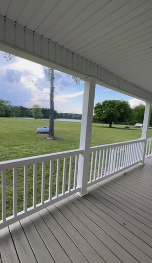 A covered porch with a view of a grassy field and a body of water. -  Can hunt on TVA land  Hunters and Fishermans Guntersville Getaway   3BR • 2BA (Langston)