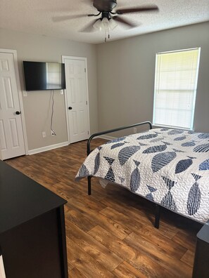 A bedroom with a bed, a ceiling fan, a TV mounted on the wall, and a window with blinds. -  Can hunt on TVA land  Hunters and Fishermans Guntersville Getaway   3BR • 2BA (Langston)
