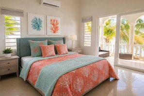 A bedroom with a bed, nightstands, a lamp, and artwork on the wall. - Luxury Oceanfront Villa in Anguilla with breathtaking Atlantic Ocean Views. (Island Harbour)