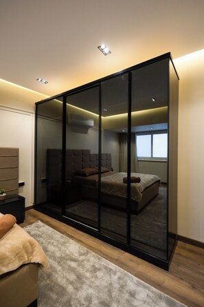 Ein modernes Schlafzimmer mit Schiebetürenschrank, einem Bett mit Kopfteil, einem Nachttisch und einem Fenster mit Vorhängen.