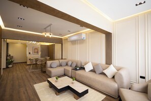 Ein modernes Wohnzimmer mit einem Ecksofa, einem Couchtisch und einem Essbereich mit Stühlen.
