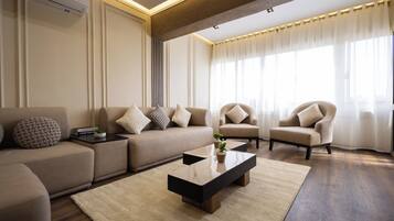 Una sala de estar moderna con sofá, sillones, una mesa de centro y un amplio ventanal con cortinas.