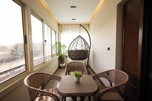 Ein Balkon mit Korbmöbeln, einem Hängesessel und einem Blumentopf.