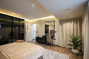 Un dormitorio moderno con cama, escritorio, silla, un espejo grande y una planta en maceta.