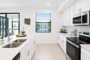 A modern kitchen with stainless steel appliances, a large window, and a view of a building outside. - Sun Seeker Lakefront Condo (Bradenton)