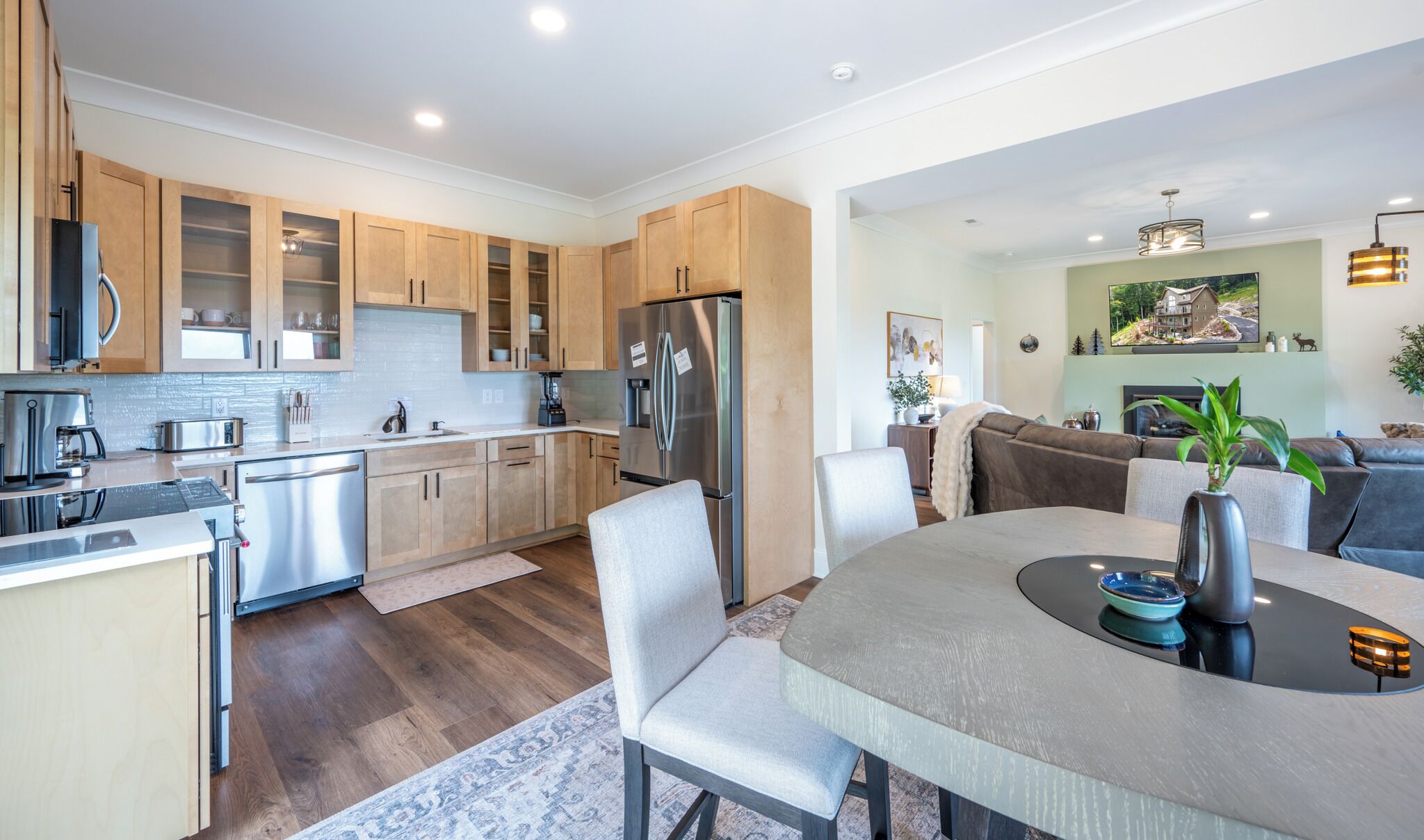 A modern kitchen with wooden cabinets, stainless steel appliances, and a dining area with a table and chairs.