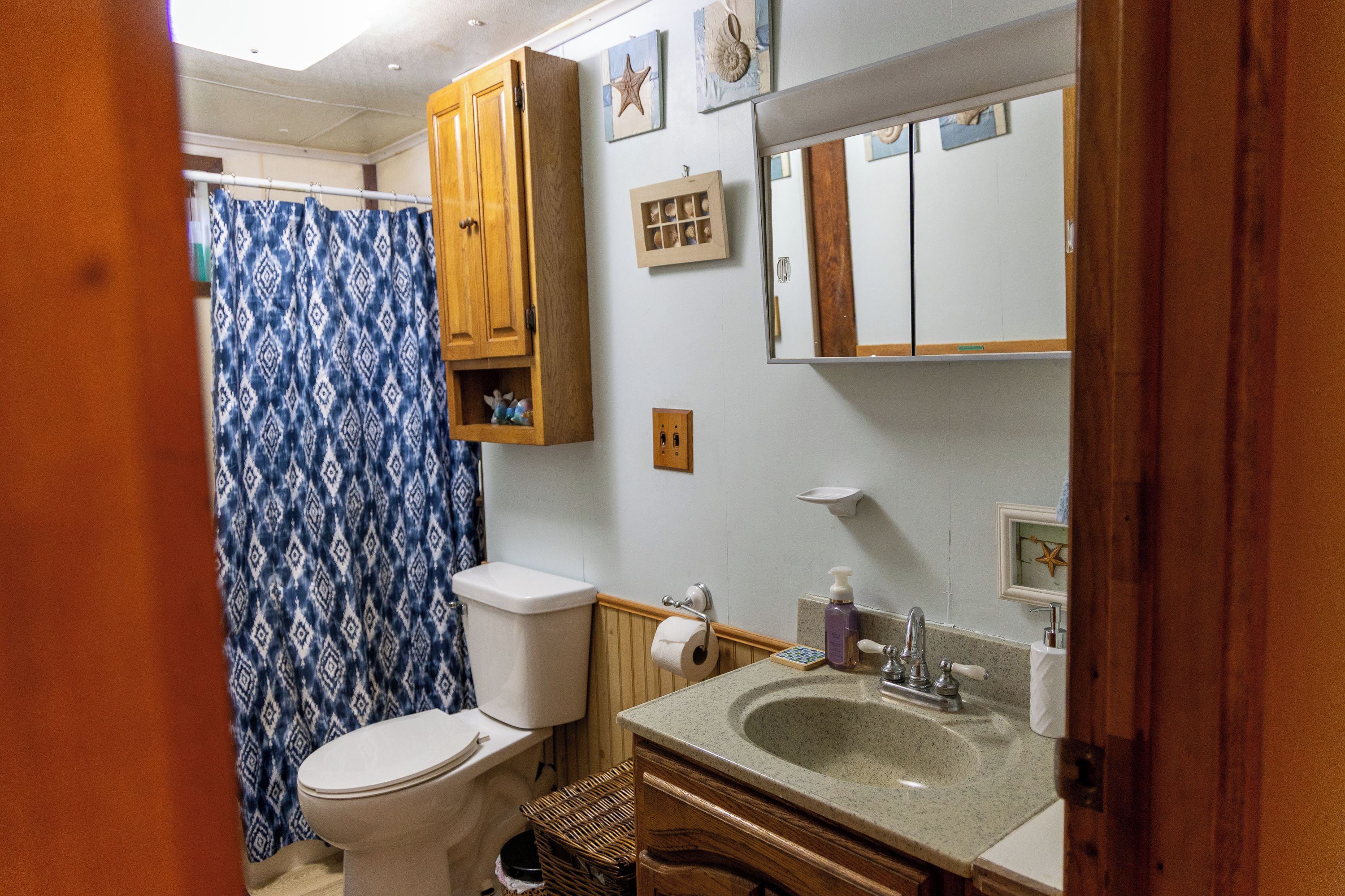 Un baño con inodoro, lavabo, espejo y cortina de ducha.
