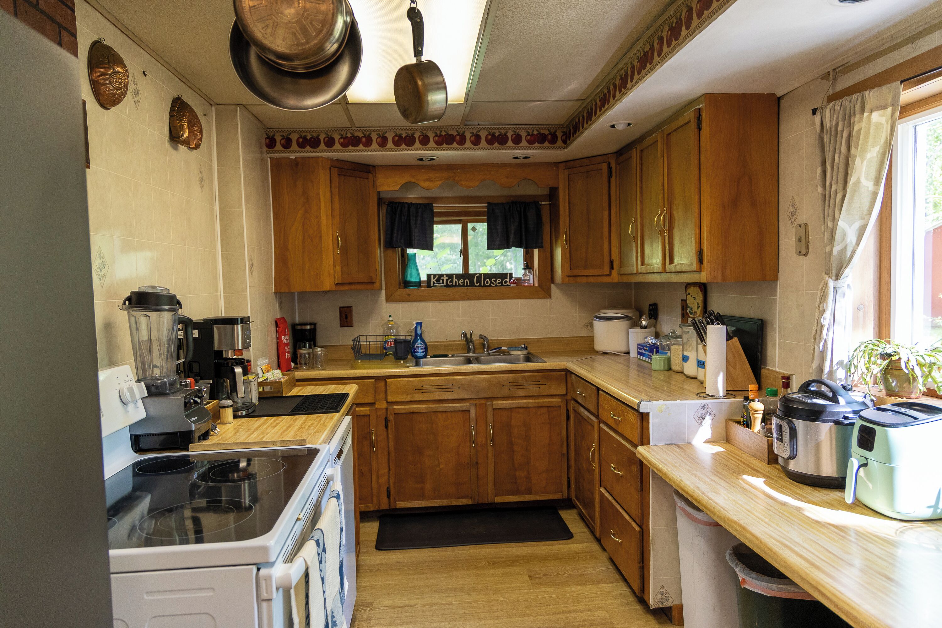 Une cuisine avec des meubles en bois, une cuisinière, une machine à café et un panneau indiquant que la cuisine est fermée.