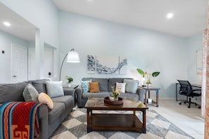 A modern living room with a sofa, coffee table, and a desk with a chair. - Renovated Top-Floor Clearwater Condo | Quiet, King Bed, Sleeps 4, Heated Pool & Gym (Clearwater)