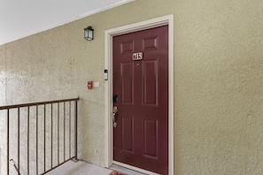 A red door with the number 715, a mailbox, and a small wall-mounted light fixture. - Renovated Top-Floor Clearwater Condo | Quiet, King Bed, Sleeps 4, Heated Pool & Gym (Clearwater)
