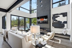 A modern living room with a fireplace, large windows, and a view of the outdoors. - Spacious 5BR Canyons Retreat with Hot Tub Near Park City Mountain (Park City)