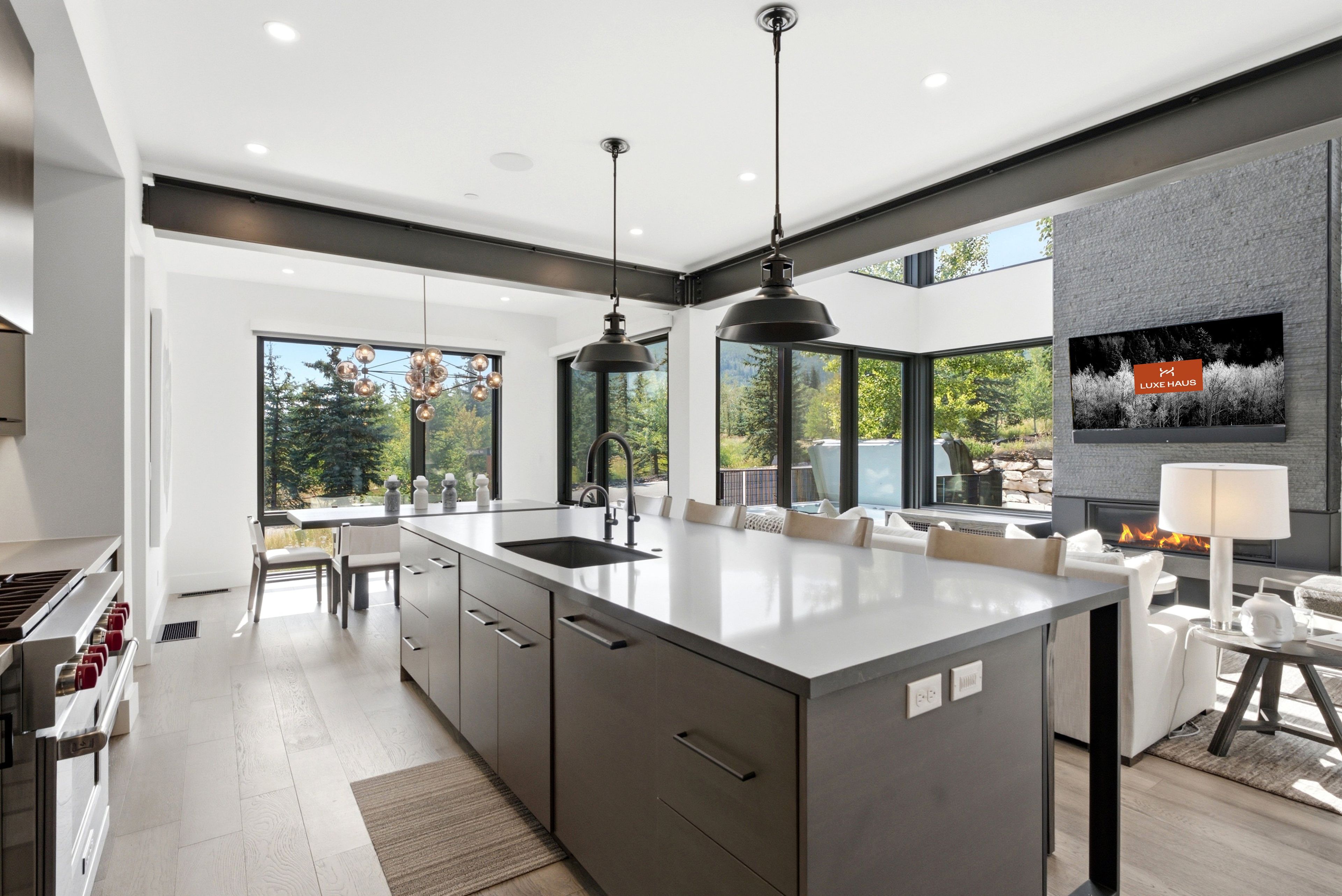 A modern kitchen with a large island, pendant lighting, and a fireplace.