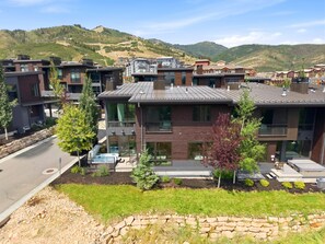 A modern residential building with a stone retaining wall, a swimming pool, and a view of a mountainous landscape. - Spacious 5BR Canyons Retreat with Hot Tub Near Park City Mountain (Park City)