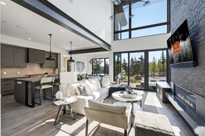 Ein modernes Interieur mit Küche, Essbereich und Wohnraum, ausgestattet mit großen Fenstern und einem Kamin.