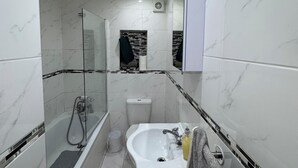 A modern bathroom with a glass-enclosed shower, a white sink, and a toilet. - Wimbledon Lodge (London)