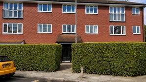 A two-story residential building with a red brick facade, multiple windows, and a yellow car parked in front. - Wimbledon Lodge (London)