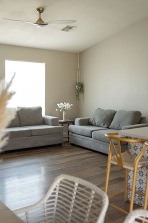 A modern living room with a grey sofa, a small table, and a ceiling fan. - 3-bedroom Desert Escape Near Saguaro Lake & Salt River (Mesa)